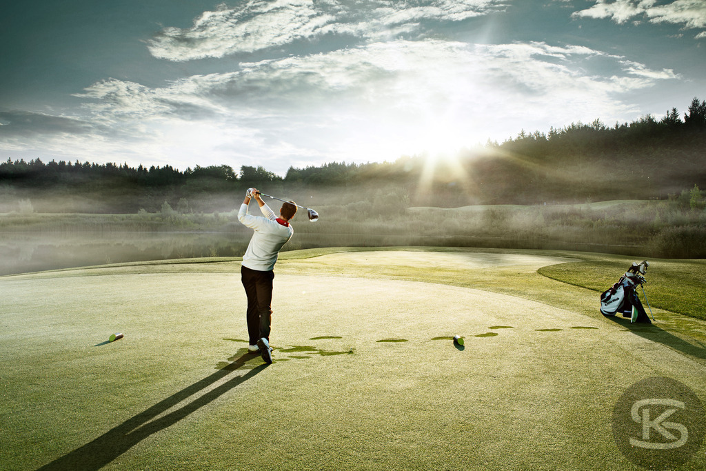 Dramatischer Golfschwung beim Sonnenaufgang auf dem Golfplatz | Erleben Sie den perfekten Moment eines Golfers auf dem Fairway, festgehalten in einem Bild mit dramatischem Lichteinfall. Der Sportler befindet sich im Follow-Through seines Abschlags, während die Morgensonne oder Abendsonne durch die Bäume bricht und eine mystische Atmosphäre schafft. - Realisiert mit Pictrs.com