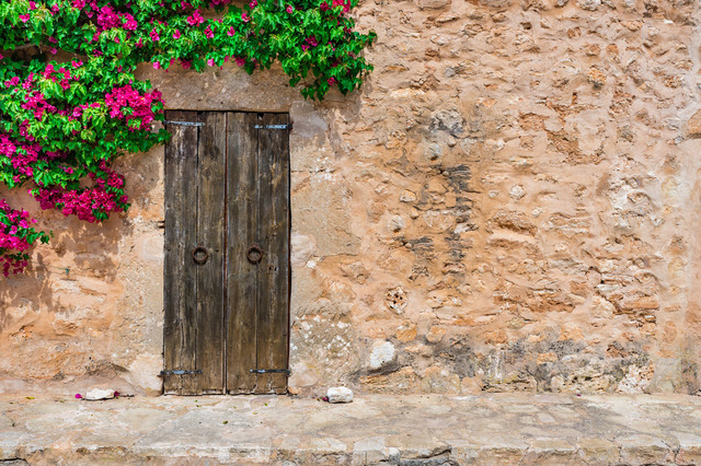 Rustic mediterranean stone house with door and bougainvillea | Idyllic mediterranean stone house with old wooden door and bougainvillea - Realisiert mit Pictrs.com