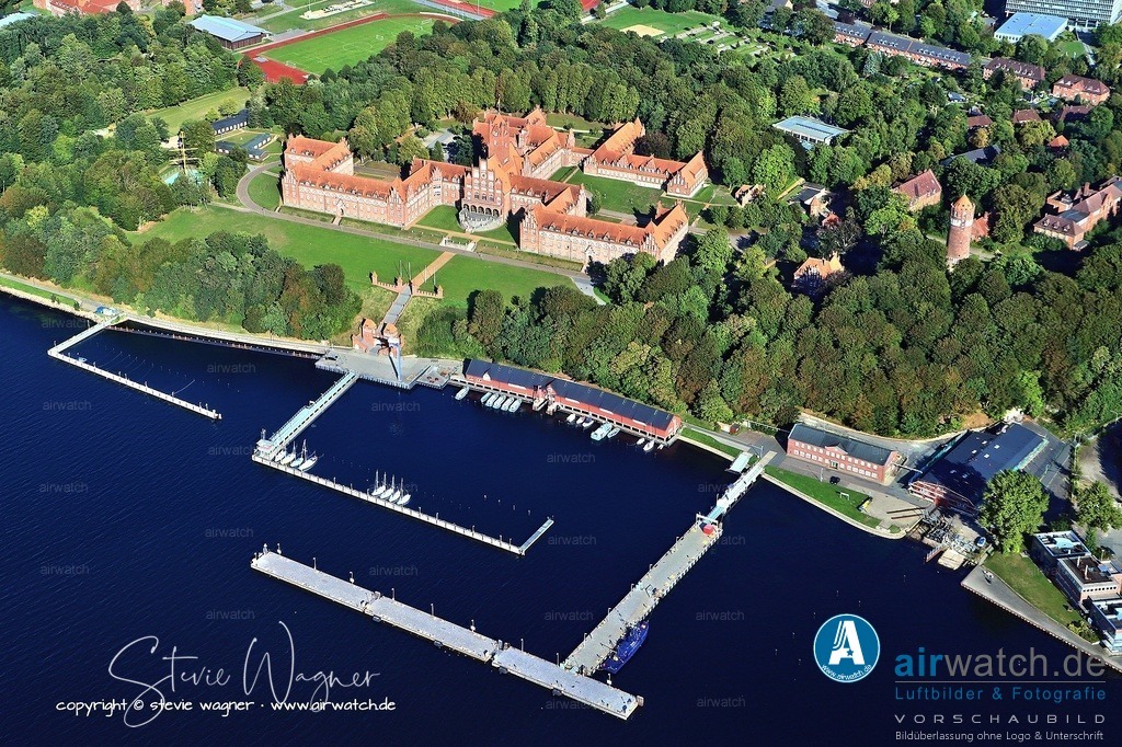 Die Marineschule Mürwik in Flensburg ist heute die zentrale Ausbildungsstätte für Offiziere der Deutschen Marine - Luftbild Anflug Marineschule Muerwik | Die Marineschule Mürwik in Flensburg ist heute die zentrale Ausbildungsstätte für Offiziere der Deutschen Marine und wird auch als „Rotes Schloss am Meer“ bezeichnet. Sie dient der Ausbildung von Offiziersnachwuchs durch verschiedene Programme, von der militärischen Grundausbildung über Offiziergrundlehrgänge bis hin zur spezialisierten Ausbildung in Navigation. Das Segelschulschiff der Schule, die „Gorch Fock“, ist eines der bekanntesten Schiffe Deutschlands und wird bei Auslandsausbildungsfahrten genutzt.