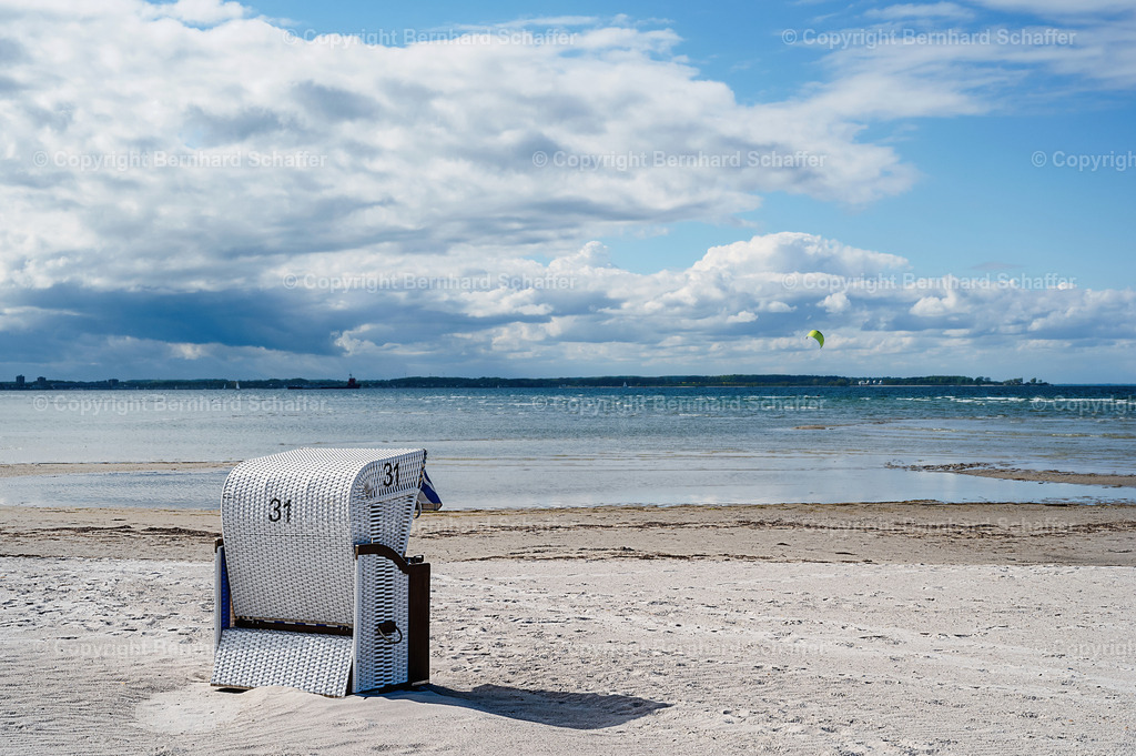 Strandkorb am Strand der Kieler Förde | Ein einzelner weißer Strandkorb steht an einem Strand in der Kieler Förde in Deutschland.  - Realisiert mit Pictrs.com