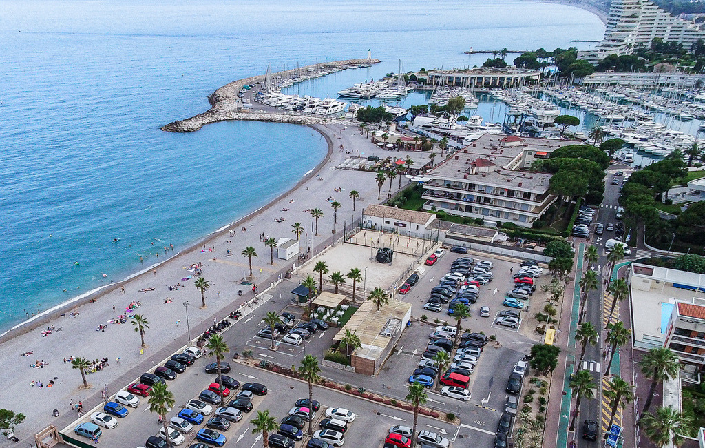 Maritimes Wandbild – Côte d’Azur zwischen Strand, Hafen und Meer | Türkisblaues Meer, heller Strand und ein mediterraner Hafen prägen diese weite Küstenansicht. Das maritime Fotomotiv bringt Urlaubsgefühl, Weite und südliche Atmosphäre als Wandbild in Wohnzimmer, Büro oder Ferienwohnung. Ideal für alle, die Küstenfotografie, Meer und mediterrane Fotokunst lieben. - Realisiert mit Pictrs.com