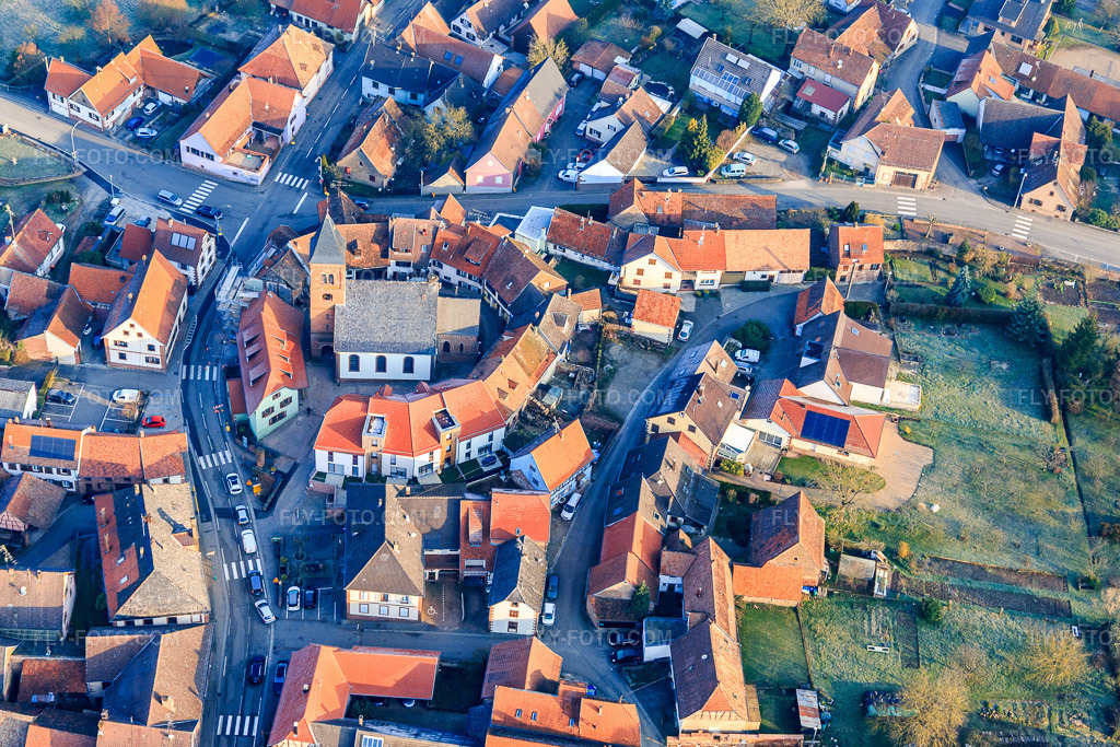 Aerial view: Lutheran-Protestant fortified church in the village center, surrounded by a ring of houses in Dossenheim-sur-Zinsel in the state Bas-Rhin, France.Photo: IMG_105329.jpg taken on 03/25/2018 by Werner Riehm/FLY-FOTO.comResolution of the original: 5253 x 3502 px