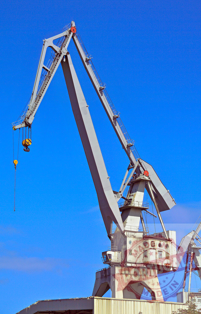 Industrial harbor crane with lifting equipment against blue sky. Spain - Bilbao | Large gantry crane standing in a port, symbolizing global shipping and logistics - Realized with Pictrs.com
