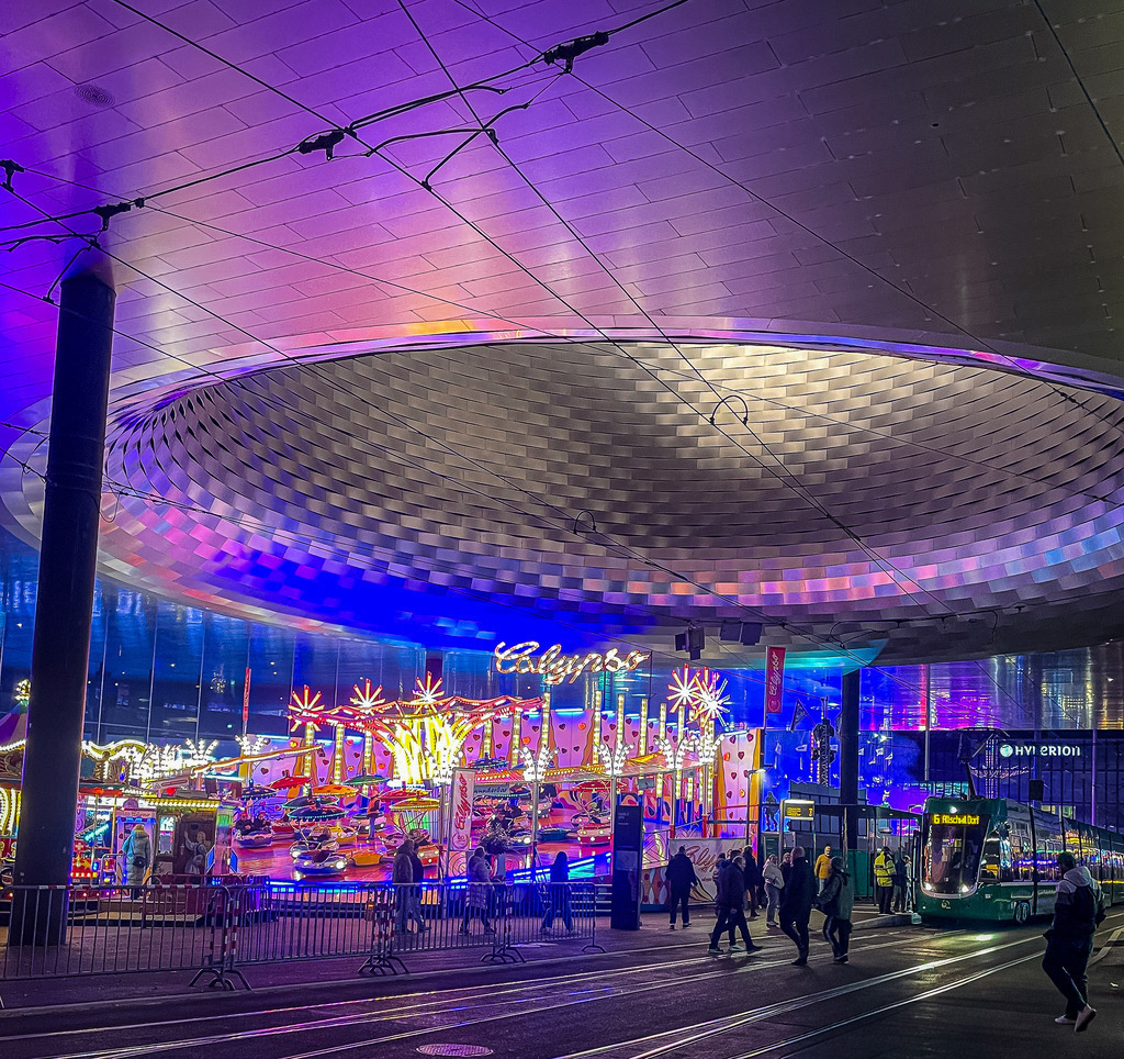 Basel Messehalle – Herbstmesse Calypso und Tram bei Nacht | Exklusive Fotokunst aus Basel: Das beeindruckende architektonische Auge der Basler Messehalle (City Lounge) fängt die Magie der Herbstmesse ein. Unter der futuristischen Hallenkonstruktion leuchten die bunten Lichter des Calypso-Fahrgeschäfts, während ein Basler Tram die Szene perfekt abrundet. Ein dynamisches, urbanes Wandbild in Galeriequalität – ideal für Liebhaber moderner Architektur und lebendiger Nachtfotografie auf Acrylglas oder Alu-Dibond. - Realisiert mit Pictrs.com