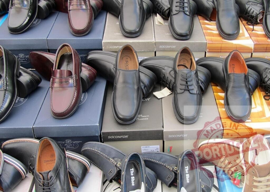 Display of a variety of mens leather shoes at retail | Various mens leather shoes on shoe boxes for sale at a market stall - Realized with Pictrs.com