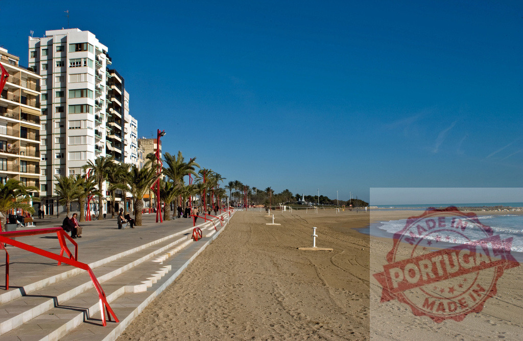 Urban beach promenade with palm trees and buildings | City people enjoying a sunny day on the beach boardwalk with ocean waves and a clear sky - Realized with Pictrs.com