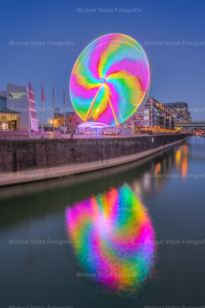 Riesenrad in Köln am Abend | Langzeitbelichtung des sich drehenden Riesenrades auf dem Platz vor dem Schokoladenmuseum in Köln. Durch die wechselnden Lichter und die Lauflichteffekte entsteht durch die Drehung dieser turbinenartige Lichteffekt. - Realisiert mit Pictrs.com