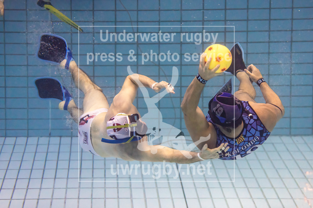 24. - 26.11.2023: Unterwasser-Rugby Champions Cup 2023  | Barcelona (Spanien) in blau gegen UWRC Wien (Österreich) in weiß. Der österreichische Meister Peter Marecek (weiß #7) greift den spanischen Kapitän José Miguel Castro (blau #19) an. - Realisiert mit Pictrs.com