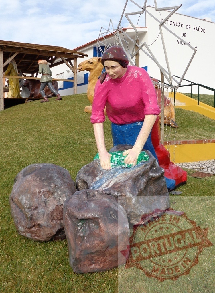 Woman washing clothes by the river in a nativity scene near a health center | Statue of a woman washing clothes in a river in a public nativity scene near a health center - Realisiert mit Pictrs.com