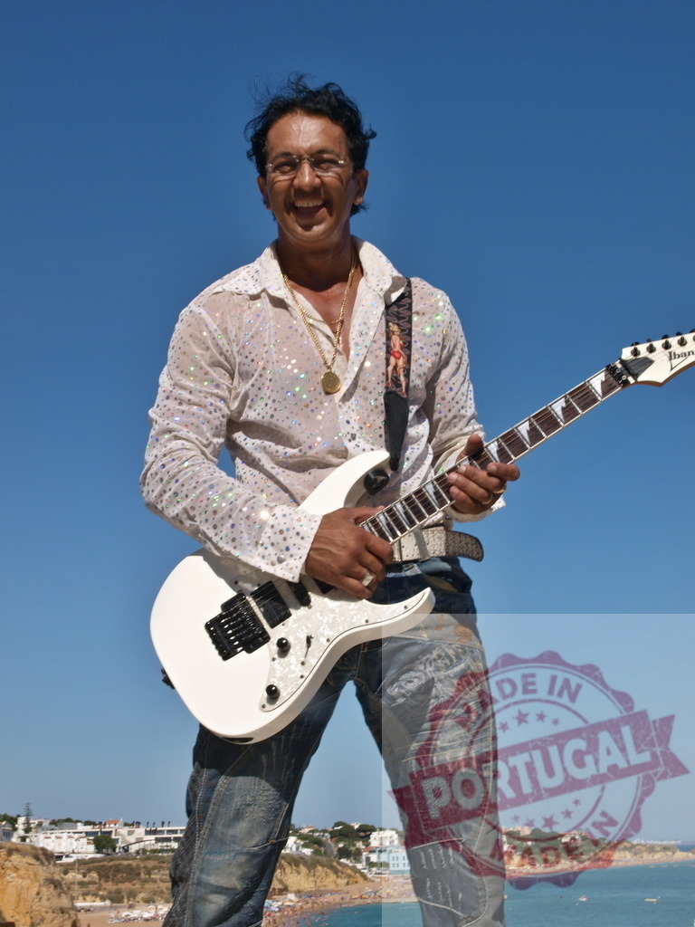 Musician playing electric guitar in front of beach in Algarve, Portugal | Guitarist playing electric guitar with beach in the background in Algarve, Portugal - Realized with Pictrs.com