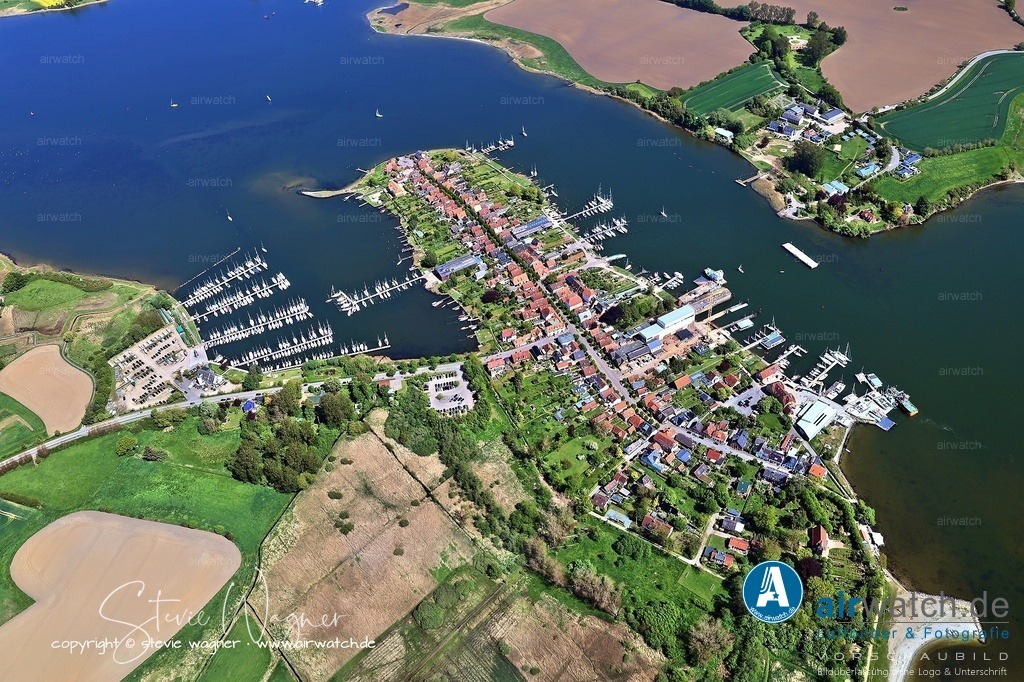 Luftbild Ostseefjord Schlei, Stadt Arnis - Der Alter Kirchenweg ist ein Fußgängerrundweg | Der Alter Kirchenweg ist ein Fußgängerrundweg, der die gesamte ehemalige Insel umrundet und einen wunderbaren Panoramablick auf Arnis, die Schlei und die umliegenden Gärten bietet. Der Weg beginnt hinter dem Parkplatz „Neuer Damm“ auf der linken Straßenseite und führt entlang idyllischer Grundstücke, oft mit direktem Zugang zur Schlei und eigenen Bootsstegen. Es ist der perfekte Weg, um die gesamte Atmosphäre des Ortes in Ruhe zu genießen.