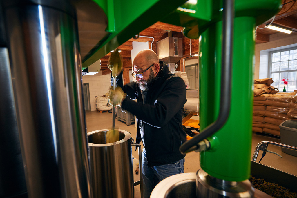 Die Ölmühle | Markt Allhau, Austria - February 09, 2018: Die Ölmühle; Herr Karl Grossschedl  befüllt die hydraulische Ölpresse mit Kernölbrei. - Realisiert mit Pictrs.com