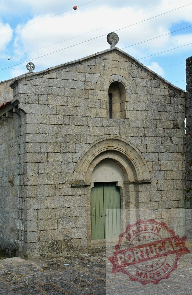 Ancient stone church building with roman arch entrance. Portugal - Norte | Old stone church with a weathered green door and ancient religious crosses on a cloudy day - Realized with Pictrs.com