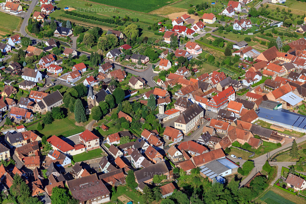 Aerial view: Village center from the northeast with Protestant Temple Saint Laurent in Steinseltz in the state Bas-Rhin, France. – Photo: IMG_082999.jpg taken on 06/26/2015 by Werner Riehm/FLY-FOTO.com – Resolution of the original: 5472 x 3648 px
