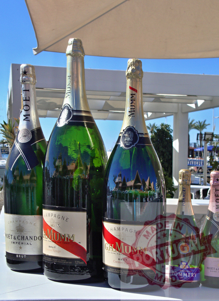 Champagne bottles on table for celebration | Various champagne bottles arranged on a table outdoors under a clear blue sky - Realisiert mit Pictrs.com