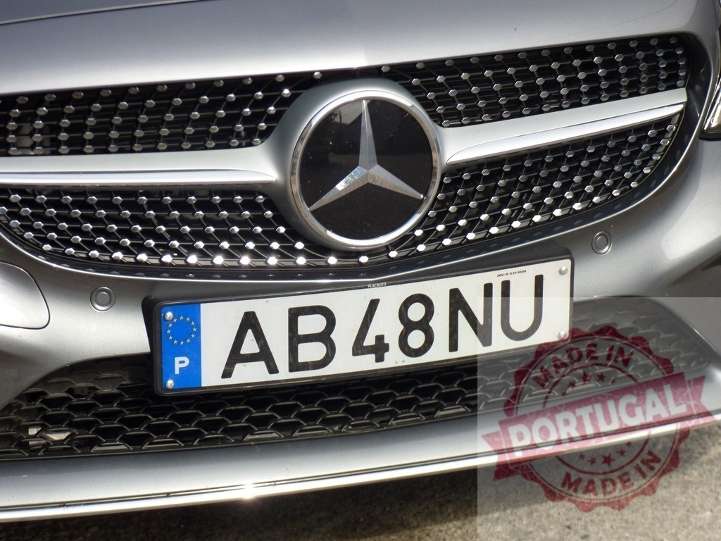 Mercedes-Benz logo and portuguese license plate showing on a gray car | Close-up of a Mercedes-Benz logo and a portuguese license plate on a gray car - Realized with Pictrs.com
