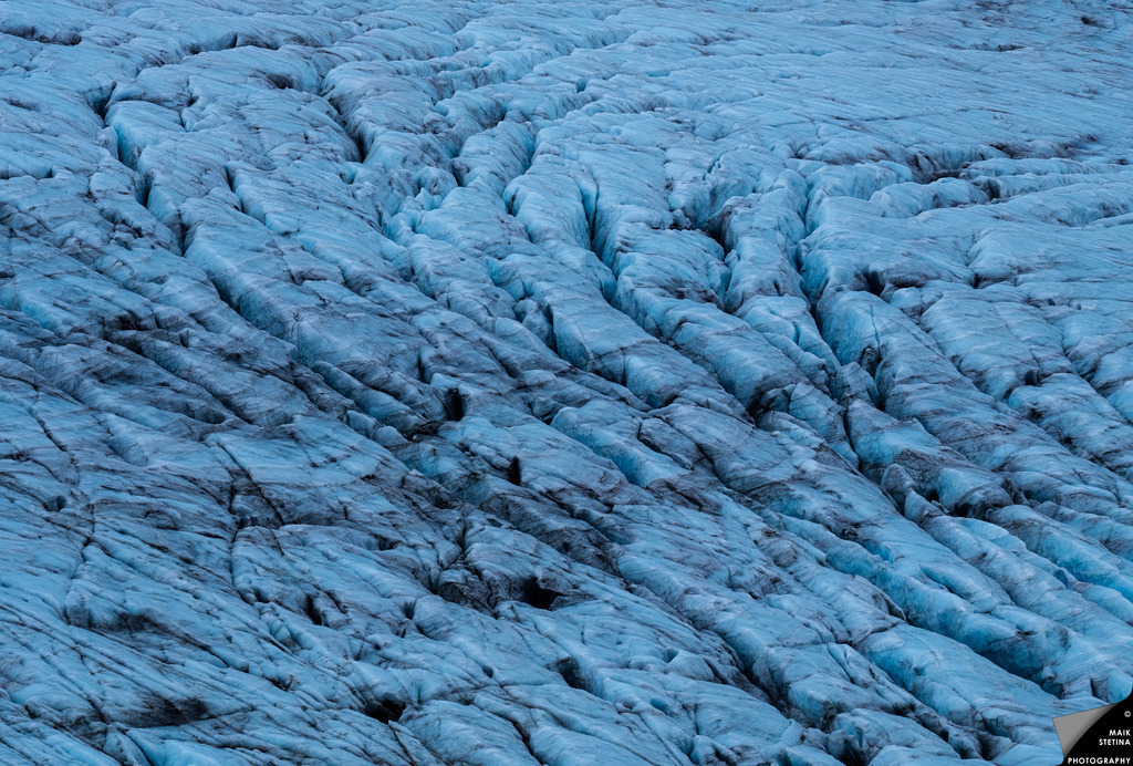 Crevasses of Marabreen | Our final hike of the 2026 trip to Norway led us from the head of Kjøsnesfjord up through the steep Lundeskaret, gaining around 900 metres of elevation into the glacial world of the southwestern reaches of Jostedalsbreen. Turquoise lakes filled with glacial water, sheer rock walls and paths polished smooth by the glaciers of the last Ice Age accompanied us towards the edge of Jostedalsbreen National Park. At around 1,200 metres, we finally stood above Marabreen, where deeply fractured ice, crevasses and visible layers revealed the complex structure of the glacier. Inspired by the work of an unknown photographer, I had long wanted to point a medium-format camera with a long telephoto lens at the intricate surface of a heavily crevassed glacier. On Marabreen, that idea finally became reality. - Realisiert mit Pictrs.com