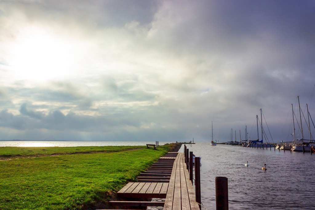 Wandbild: Yachthafen in Orth auf Fehmarn | Dieses Wandbild im Querformat zeigt den Yachthafen in Orth auf Fehmarn im Herbst. Am Himmel sind zahlreiche Wolken zu sehen. - Realisiert mit Pictrs.com