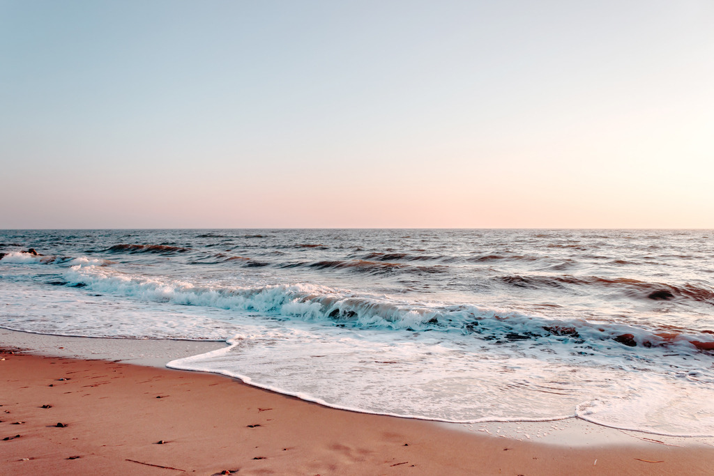 Wandbild: Küstenauftakt – Erwachen am Horizont | Ein Moment voller Reinheit und neuer Möglichkeiten. Dieses Wandbild fängt das sanfte Licht eines beginnenden Morgens an der Ostsee ein. Während der Horizont in zarten Pastelltönen von Apricot und Rosa leuchtet, rollt eine erste, sanfte Welle am Strand aus und hinterlässt ein filigranes Muster aus weißem Schaum. Eine poetische und belebende Komposition, die die frische Ruhe eines Sonnenaufgangs direkt in Ihr Zuhause bringt und für eine Atmosphäre voller Klarheit sorgt. - Realisiert mit Pictrs.com