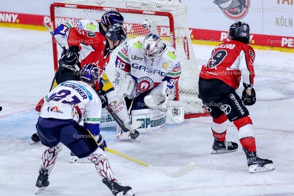 KEC23042501092 | 23.04.2025, Eishockey, DEL Finale Play-offs, Kölner Haie - Eisbären Berlin, Finale Spiel 3, Lanxess-Arena Köln: Gregor MacLeod (Kölner Haie #89) und Justin Schütz (Kölner Haie #10) im Zweikampf um den Puck vor dem Tor von Goalie Jake Hildebrand (Eisbaeren Berlin #30) 