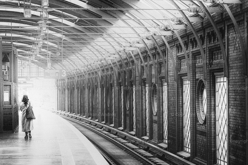Bahnhof Berlin Hackescher Markt | Eine Frau geht allein auf einem Bahnsteig in einem der schönsten Bahnhöfe von Berlin - Hackescher Markt. Straßenfotografie aus Berlin in schwarz und weiß. - Realisiert mit Pictrs.com