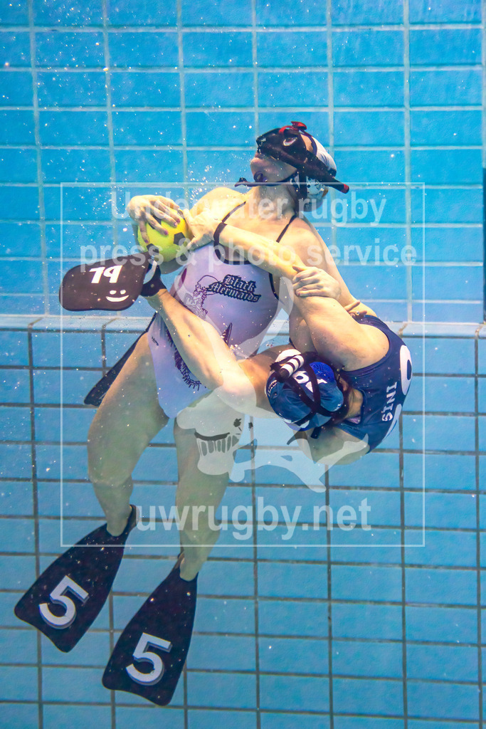 24. - 26.11.2023: Unterwasser-Rugby Champions Cup 2023  | Strafstoß im Damen-Spiel: Amager Uv-Rugby (Dänemark) in blau gegen Black Mermaids (Schweden) in weiß. Die schwedische Torwartin Ann-Sofi Krakau (weiß #5) ist gerade beim Auftauchen nachdem sie während des Strafstoß ihrer dänischen Gegnerin Sini Korppi-Tommola (blau #79) den Ball im einsgegeneins abnehmen konnte. Sobald sie die Wasseroberfläche erreicht gilt der Straßstoß als beendet und gehalten. - Realisiert mit Pictrs.com