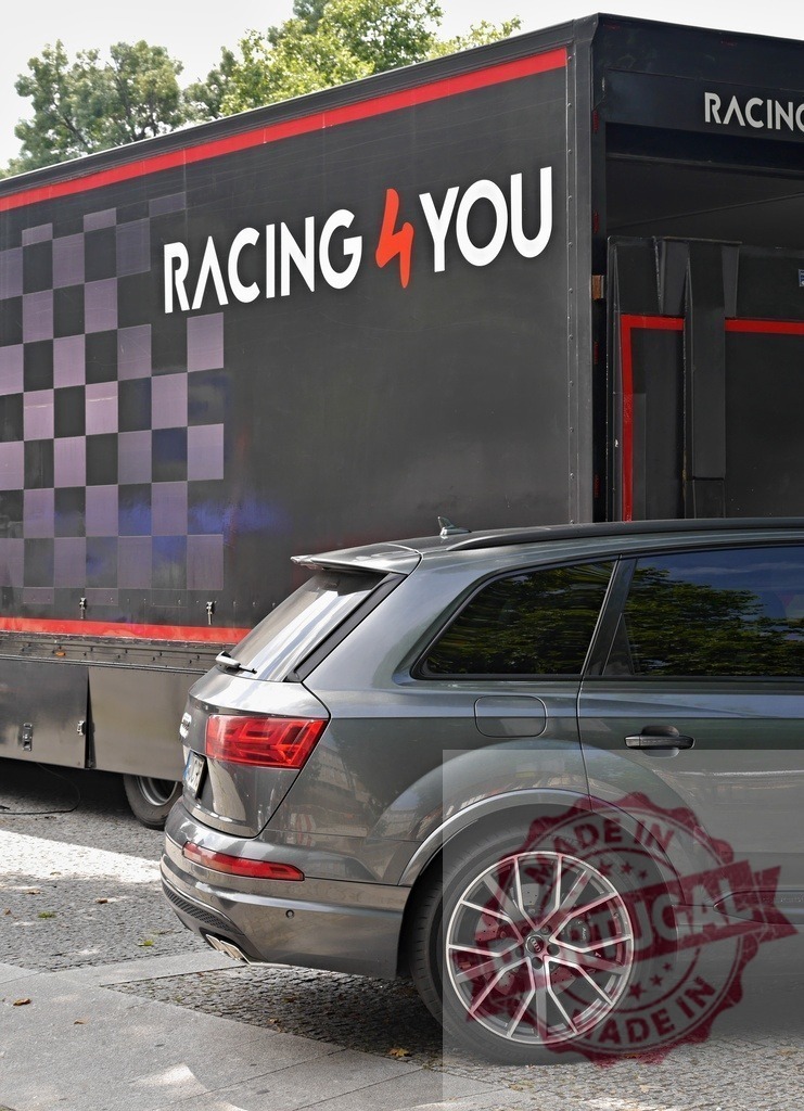 Audi SUV parked next to Racing 4 You trailer | Audi Q7 SUV parked at event with a professional racing team trailer - Realized with Pictrs.com