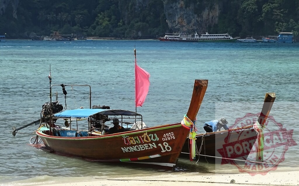 Traditional thai longtail boats mooring near tropical beach in Thailand | Two traditional thai longtail boats mooring near a tropical beach with turquoise water - Realized with Pictrs.com
