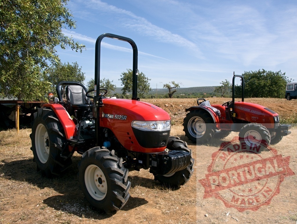 Branson 5025R and Branson 310 tractor models parked outdoors | Two red Branson tractors parked on dry ground under a clear blue sky - Realized with Pictrs.com