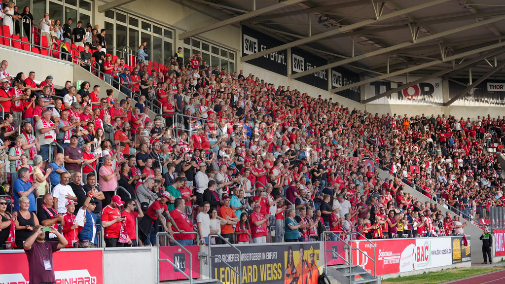 Fußball, Herren, Saison 2025/2026, Regionalliga Nordost, 1. Spieltag, FC Rot-Weiß Erfurt vs. FSV 63 Luckenwalde, Freitag 25.07.2025, Steigerwaldstadion Erfurt, | Fußball, Herren, Saison 2025/2026, Regionalliga Nordost, 1. Spieltag, FC Rot-Weiß Erfurt vs. FSV 63 Luckenwalde, Freitag 25.07.2025, Steigerwaldstadion Erfurt, Im Bild: Erfurter Fans stehen im Steigerwaldstadion zur Vereinshymne - Realisiert mit Pictrs.com