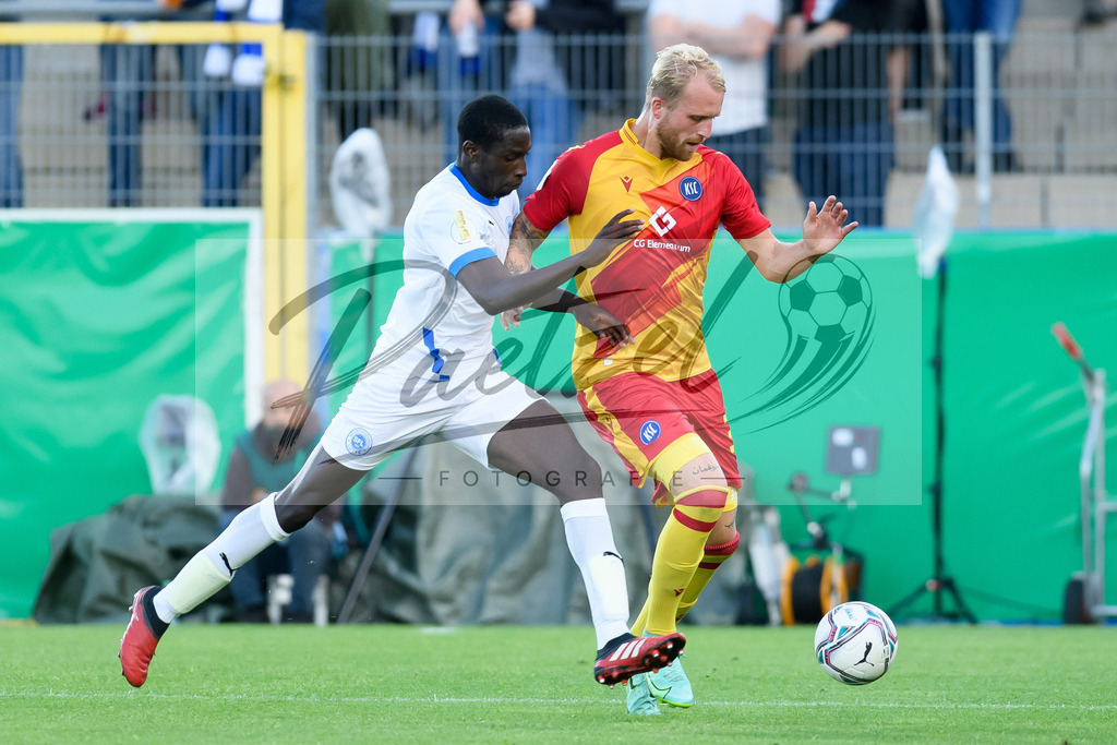 LOTKSC20210809_048 | Fussball, Herren: Komlan Fionouke (Sportfreunde Lotte) und Philipp Hofmann (Karlsruher SC) im Zweikampf beim Spiel der 1. Runde im DFB-Pokal zwischen SF Lotte und Karlsruher SC im Stadion am Lotter Kreuz am 09.08.2021 in Lotte, Deutschland.DFB / DFL REGULATIONS PROHIBIT ANY USE OF PHOTOGRAPHS AS IMAGE SEQUENCES AND/OR QUASI-VIDEO. - Realisiert mit Pictrs.com