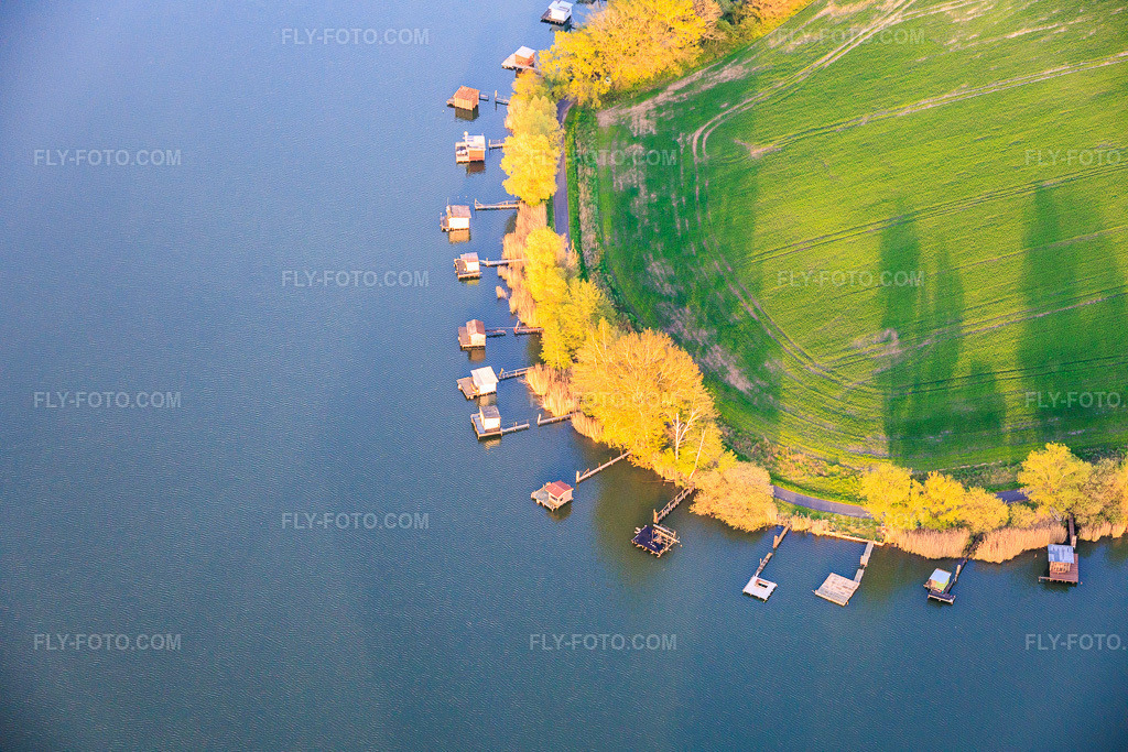 Aerial view: Boardwalks with fishing huts line the shore of Lake Etang du Welschhof. in Puttelange-aux-Lacs in the state Moselle, France. – Photo: IMG_154813.jpg taken on 04/17/2026 by Werner Riehm/FLY-FOTO.com – Resolution of the original: 6000 x 4000 px