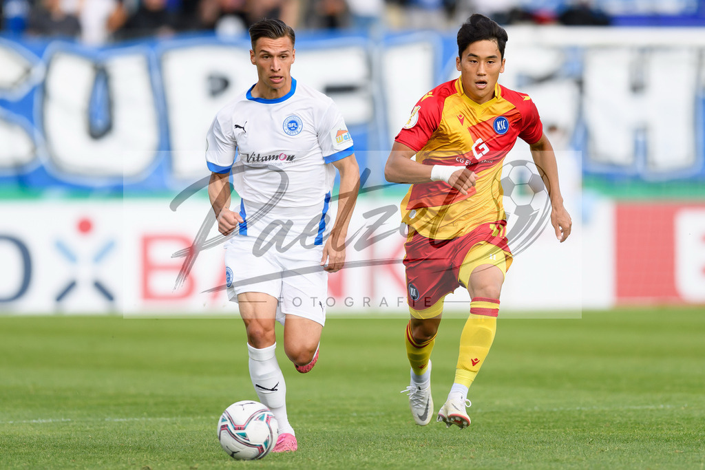 LOTKSC20210809_004 | Fussball, Herren: Tyson Richter (Sportfreunde Lotte) und Kyoung-rok Choi (Karlsruher SC) im Zweikampf beim Spiel der 1. Runde im DFB-Pokal zwischen SF Lotte und Karlsruher SC im Stadion am Lotter Kreuz am 09.08.2021 in Lotte, Deutschland.DFB / DFL REGULATIONS PROHIBIT ANY USE OF PHOTOGRAPHS AS IMAGE SEQUENCES AND/OR QUASI-VIDEO. - Realisiert mit Pictrs.com