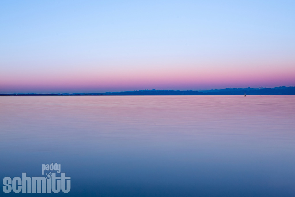 Romantische blau-rote Stunde am Bodensee | Die blaue Stunde taucht den Bodensee in ein faszinierendes Farbenspiel aus seichten Blau- und warmen Rottönen. Das sanfte Licht über dem Wasser schafft eine romantische und zugleich ruhige Atmosphäre, die den besonderen Zauber des Sees am Abend einfängt. - Realisiert mit Pictrs.com