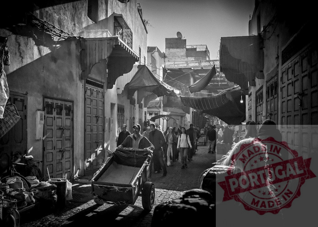 Worker pushing cart in crowded alley of medina in fes, morocco | Moroccan worker pushing a cart along a busy alley in the medina of fes, morocco, black and white photography - Realisiert mit Pictrs.com