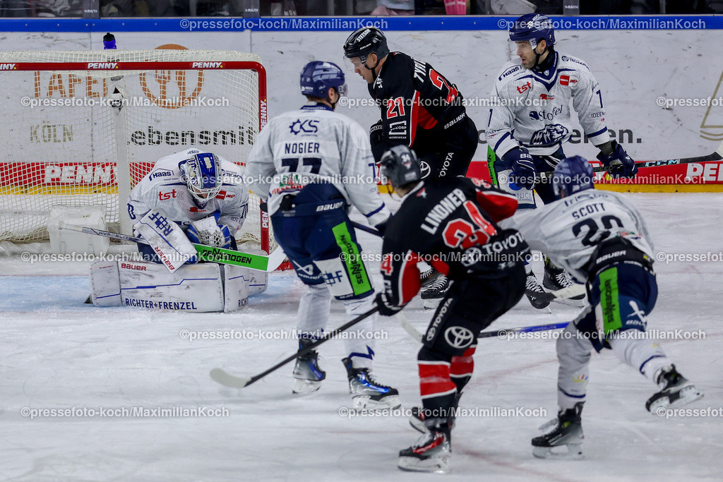 KEC22122401052 | 22.12.2024, Eishockey, DEL, Kölner Haie - Straubing Tigers, Spieltag 29, Lanxess-Arena Köln: Goalie Zane McIntyre (Straubing Tigers #70) verteidigt gegen Juhani Tyrväinen (Kölner Haie #21) und Elias Lindner (Kölner Haie #34)