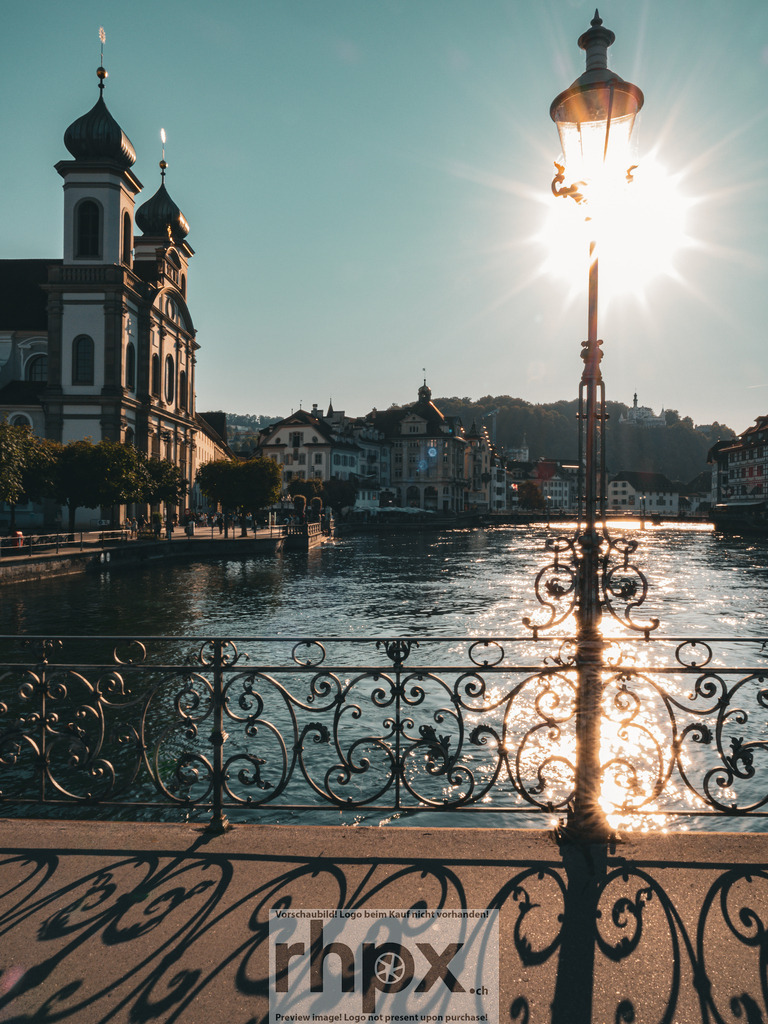 Sommerliches Luzern | Licht. Geschichte. Fluss.
Die warme Sommersonne taucht die Ufer der Reuss in ein goldenes Licht und lässt Luzern erstrahlen. Das Spiel von Licht und Schatten auf der Brücke fängt die friedliche Atmosphäre eines Nachmittags in der Leuchtenstadt perfekt ein.
Wähle unter "Produktauswahl" dein Wunschformat: Vom klassischen Wandbild über Puzzle &amp; Tassen bis zum digitalen Download (z.B. als Handy-Hintergrund).
 - Realisiert mit Pictrs.com