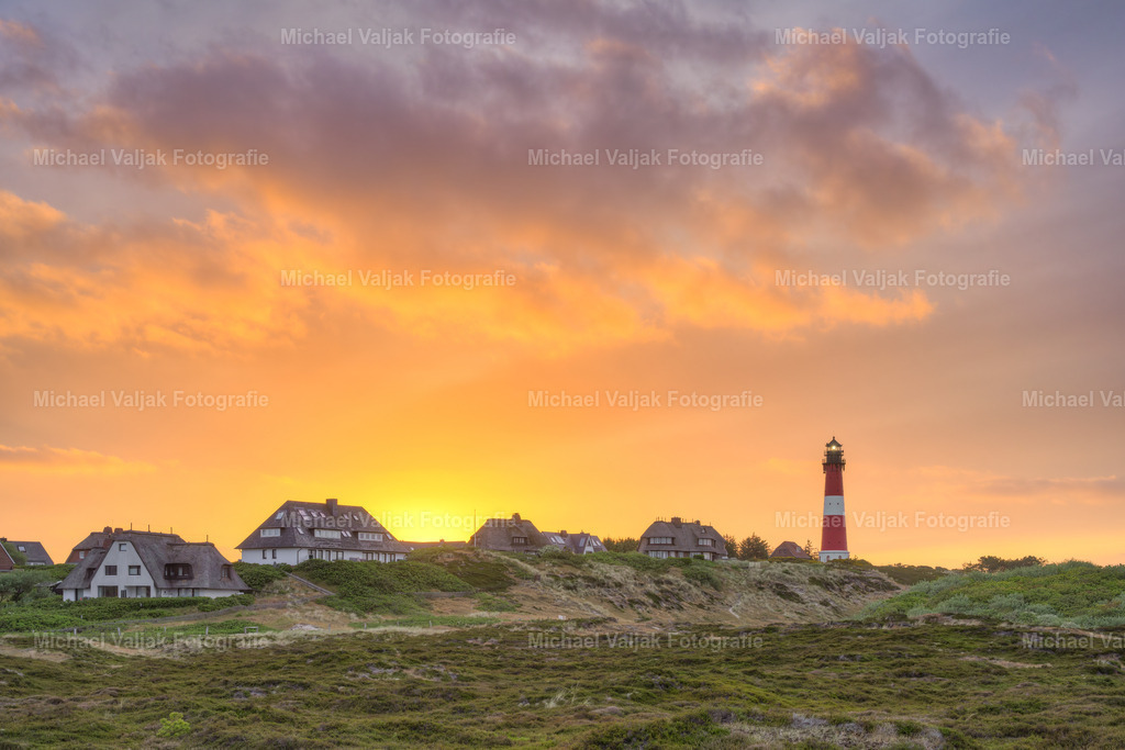 Sonnenaufgang in Hörnum auf Sylt | Der Leuchtturm von Hörnum ist ein markantes Wahrzeichen auf der Insel Sylt. Am frühen Morgen, wenn die Sonne über dem Horizont aufsteigt, bietet sich ein malerischer Anblick. Die roten und orangen Farben des Himmels lassen den Leuchtturm und die Umgebung in einem warmen Licht erstrahlen. Der Sonnenaufgang in Hörnum ist ein Erlebnis, das man nicht so schnell vergisst. - Realisiert mit Pictrs.com