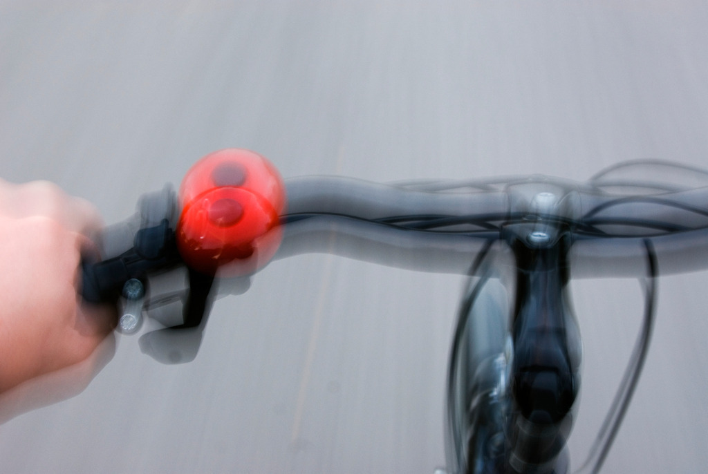 Fahrradlenkstange mit Hand während der Fahrt | Austria - September 23, 2007: Fahrradlenkstange mit Hand und roter Klingel während der Fahrt - Realisiert mit Pictrs.com