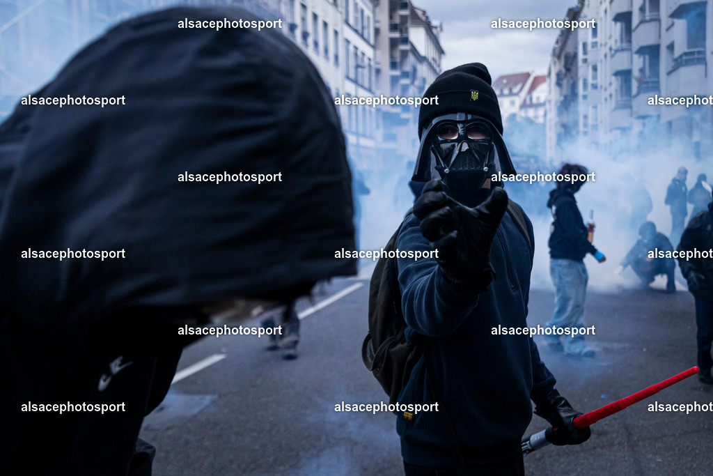 9L6A6639 | Strasbourg, France, 24 octobre 2026. Des manifestants affrontent les forces de l’ordre lors d’une mobilisation dans le centre-ville de Strasbourg. Des policiers interviennent pour disperser des groupes de manifestants, tandis que des gaz lacrymogènes sont utilisés. Des affrontements, des jets de projectiles et des dégradations sont observés dans plusieurs rues. Des barricades et des véhicules en feu témoignent de la tension qui règne en marge de la mobilisation. - Realisiert mit Pictrs.com