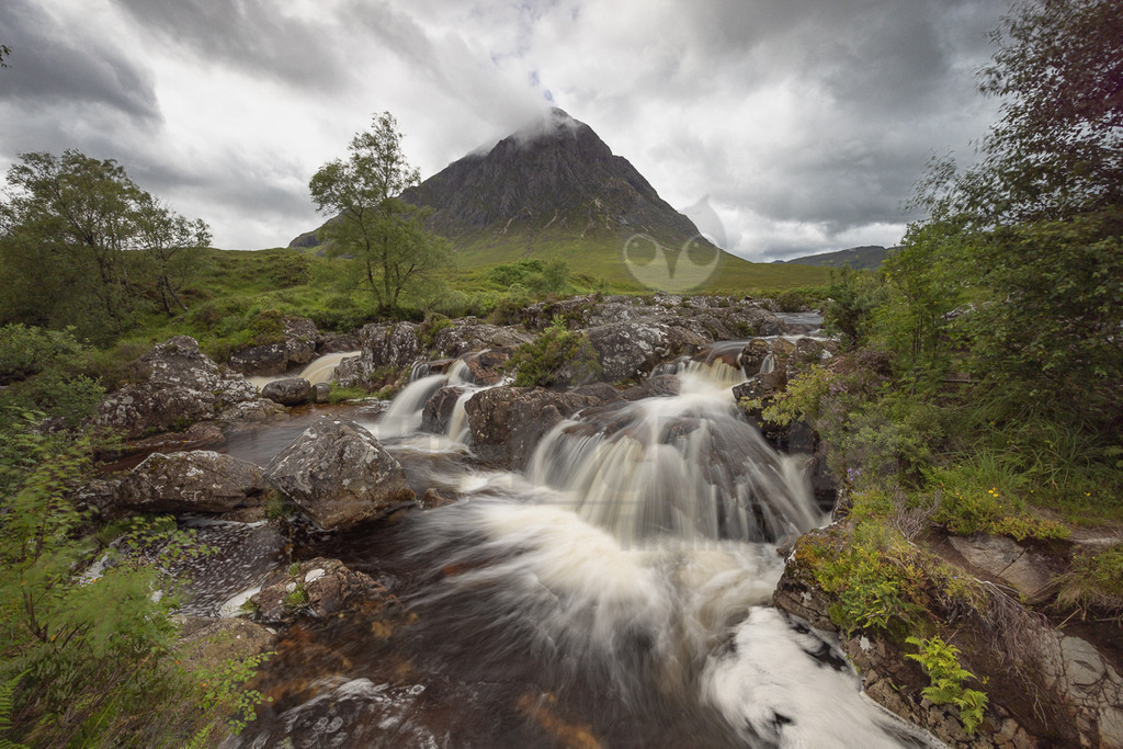 20220725143430-3 | Diese Aufnahme fängt die wilde Schönheit der schottischen Highlands ein. Der Fluss, der über die Felsen stürzt, ist ein lebendiges Beispiel für die Kraft der Natur. Der Berg im Hintergrund, vermutlich ein Teil der Grampian Mountains, verleiht der Landschaft eine beeindruckende Tiefe und Größe. Die üppige Vegetation und der bewölkte Himmel tragen zur typischen, oft feuchten und dramatischen Atmosphäre Schottlands bei. Es ist ein Bild, das die raue und unberührte Natur Großbritanniens widerspiegelt. - Realisiert mit Pictrs.com