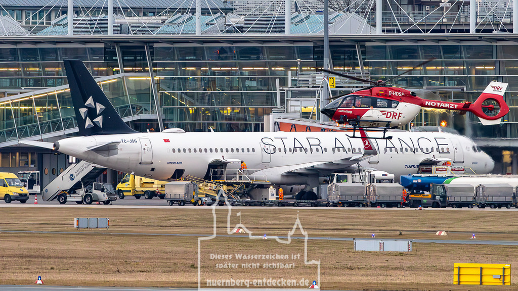 Albrecht Dürer Airport  Nürnberg, 15.03.2025 | Ein Rettungshubschrauber der DRF Luftrettung, ein Airbus H145 mit der Kennung D-HDSF, schwebt über dem Vorfeld des Albrecht Dürer Airport Nürnberg. Im Hintergrund steht ein Airbus A321 der Turkish Airlines in Star Alliance-Lackierung, während das Flugzeug für den nächsten Flug vorbereitet wird. - Realisiert mit Pictrs.com