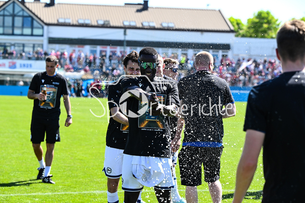 SpVgg Unterhaching - Arminia Bielefeld | die Mannschaft aus Bielefeld feiert zusammen mit den Fans dein Sieg und den Aufstieg in Unterhaching / Bierdursche / Bier / Freude / Happy / Gluecklich / 3. Liga: SpVgg Unterhaching - Arminia Bielefeld, Uhlsport Park am 11.05.2025 / Merveille BIANKADI (Arminia Bielefeld 17)