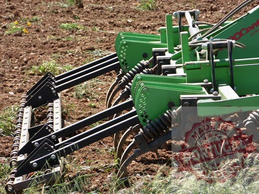 Farm equipment cultivating soil in an agricultural field | Green cultivator preparing brown soil in a spring agricultural field - Realisiert mit Pictrs.com