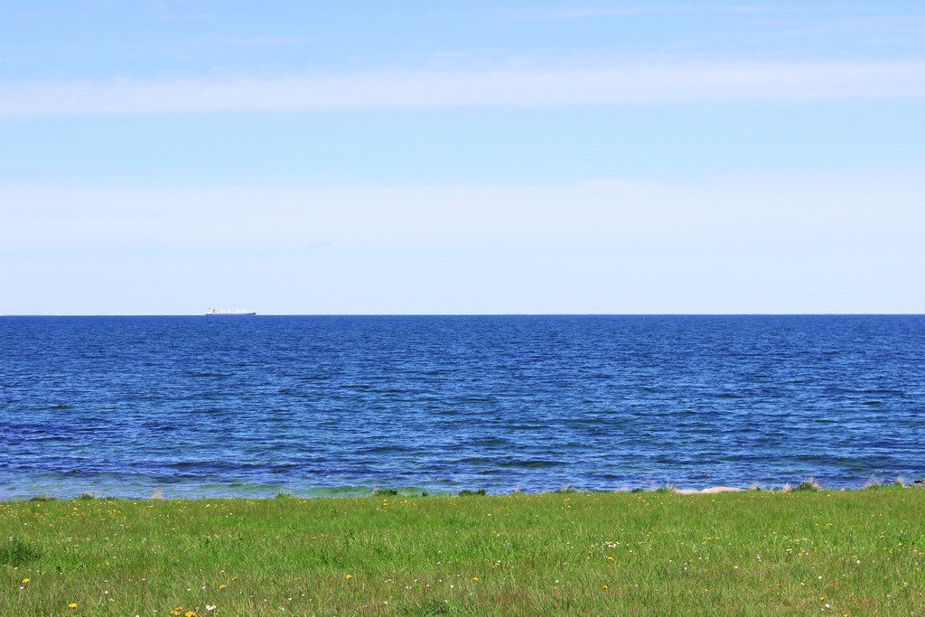 Wandbild: Frühling in Puttgarden auf Fehmarn | Dieses Wandbild im Querformat zeigt Puttgarden auf Fehmarn im Frühling. Am blauen Himmel sind nur wenige Schleierwolken zu sehen.  - Realisiert mit Pictrs.com