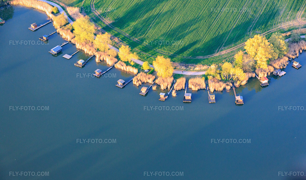 Aerial view: Boardwalks with fishing huts line the shore of Lake Etang du Welschhof. in Puttelange-aux-Lacs in the state Moselle, France. – Photo: IMG_154804.jpg taken on 04/17/2026 by Werner Riehm/FLY-FOTO.com – Resolution of the original: 6000 x 3537 px