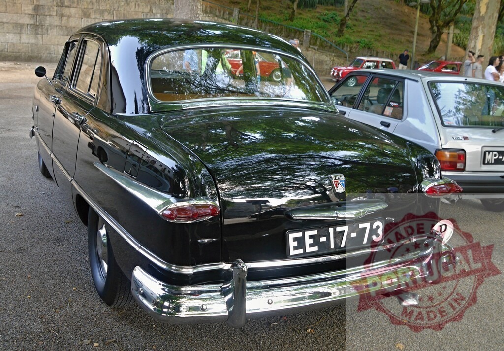 Black vintage Ford sedan parked at car show | Rear view of a classic black Ford sedan showing chrome details and reflections - Realized with Pictrs.com