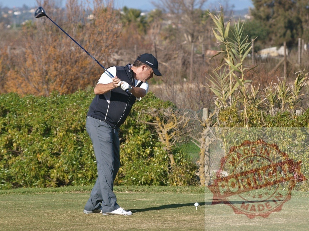 Golfer swinging golf club on course during sunny day | Golfer concentrating while swinging golf club on a sunny day on the course - Realisiert mit Pictrs.com