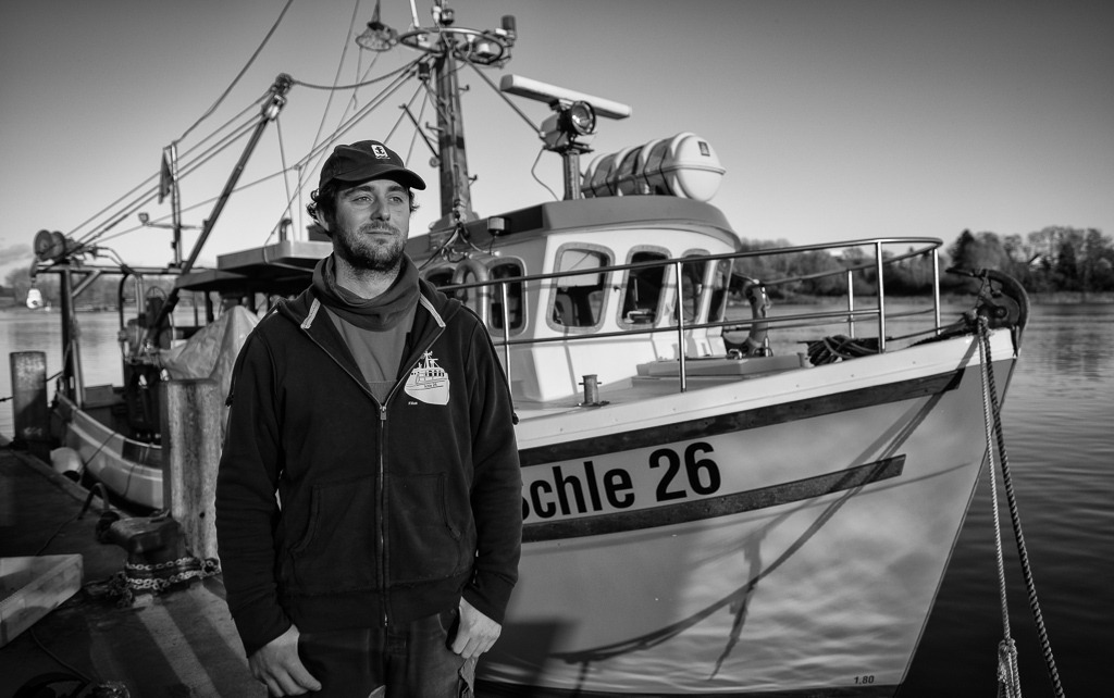 fischer-DSF0086 | Christian Ross ist der jüngste unter den Fischern vom Holm in Schleswig an der Schlei. Er fischt am liebsten allein in seinem Kutter "Schle 26" auf der Ostsee. Hier steht Christian Ross am Liegeplatz des Schiffes im Hafen von Kappeln. - Realisiert mit Pictrs.com