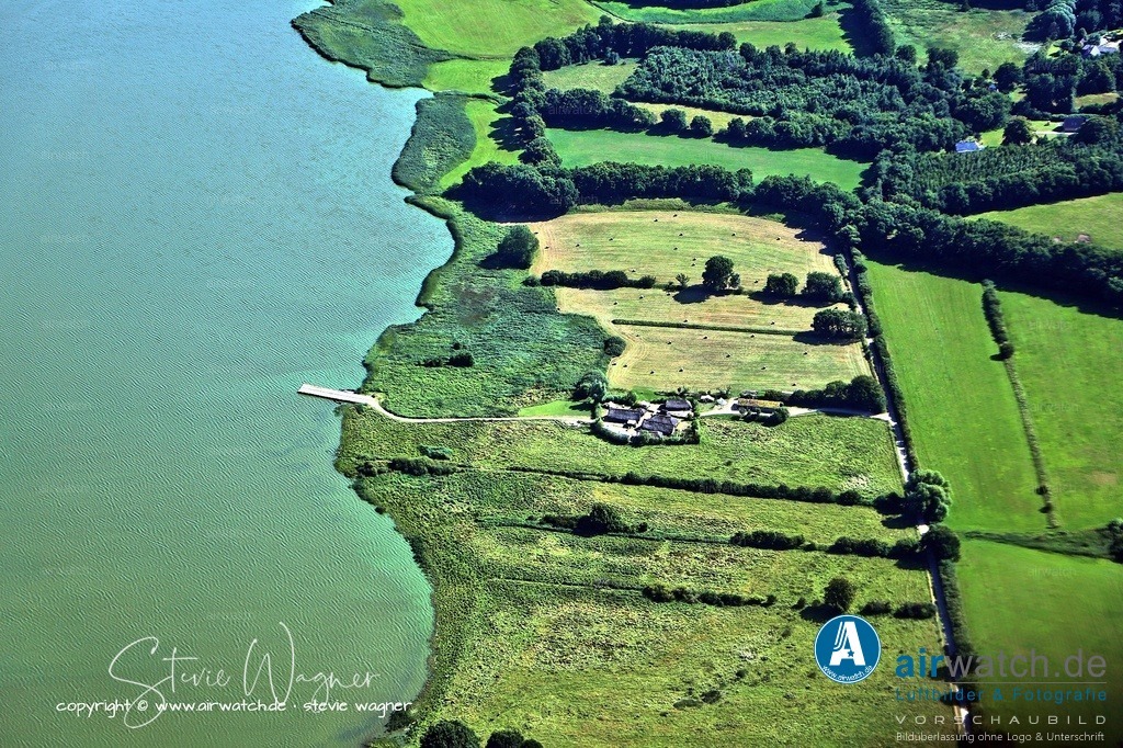 Haithabu - Niedergang und archäologische Bedeutung - Luftbild | Haithabu wurde 1050 durch einen Konflikt zwischen norwegischen und dänischen Königen schwer beschädigt und 1066 endgültig von den Westslawen geplündert.  Danach verlagerte sich die Siedlungstätigkeit nach Schleswig, und Haithabu wurde aufgegeben. - Die Stadt blieb unüberbaut, was die außergewöhnliche Erhaltung archäologischer Funde ermöglichte – besonders von organischen Materialien wie Holz, Leder und Textilien dank des feuchten Bodens. Bis heute sind nur etwa 5 % der Fläche ausgegraben.